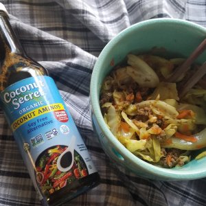 eggroll in a bowl with a bottle of coconut aminos next to it