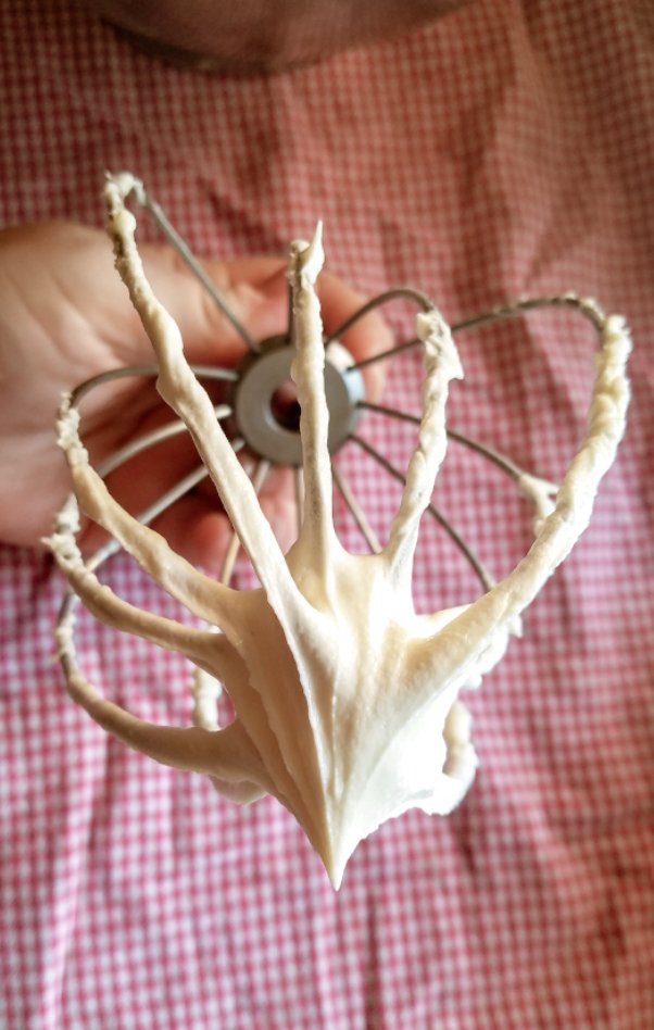 gluten free buttercream frosting with sift peaks off of a whisk