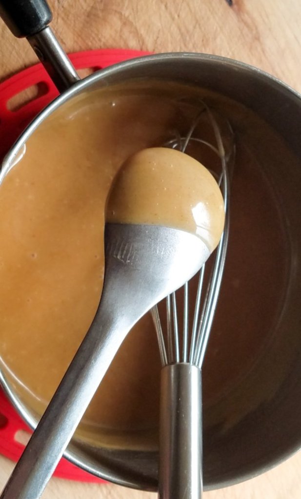 homemade caramel sauce coating the back of a spoon