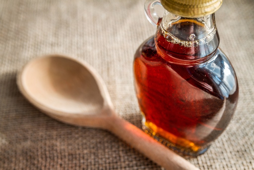 maple syrup in a glass bottle with a wooden spoon.