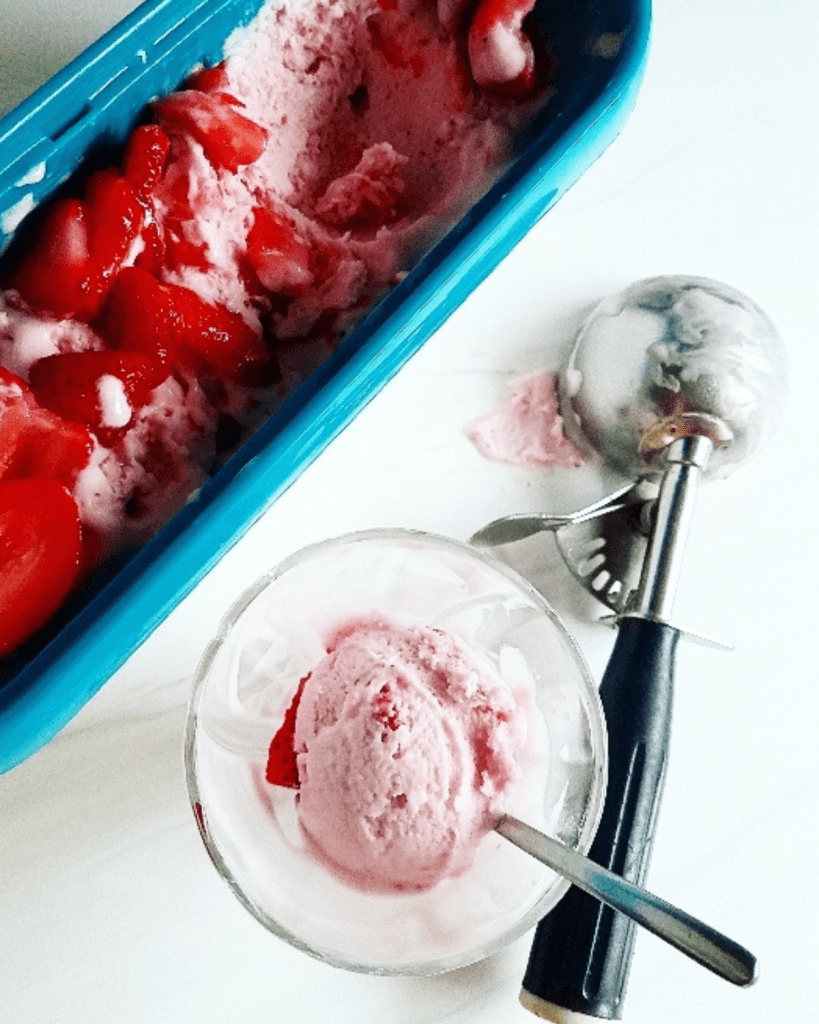 Keto Strawberry Ice Cream in a container and scooped into a glass dish