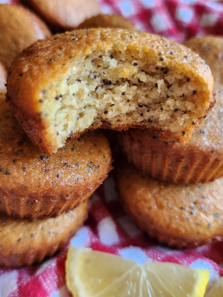 Stack of lemon poppyseed muffins with the top one missing a bite
