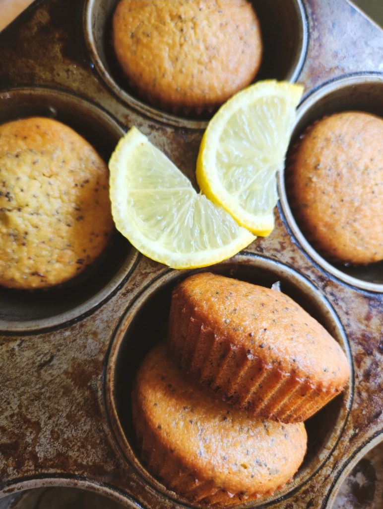 Gluten free keto lemon poppyseed muffins in muffin tin with an slice of lemon
