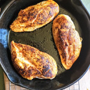 three chicken breasts seared in a cast iron skillet