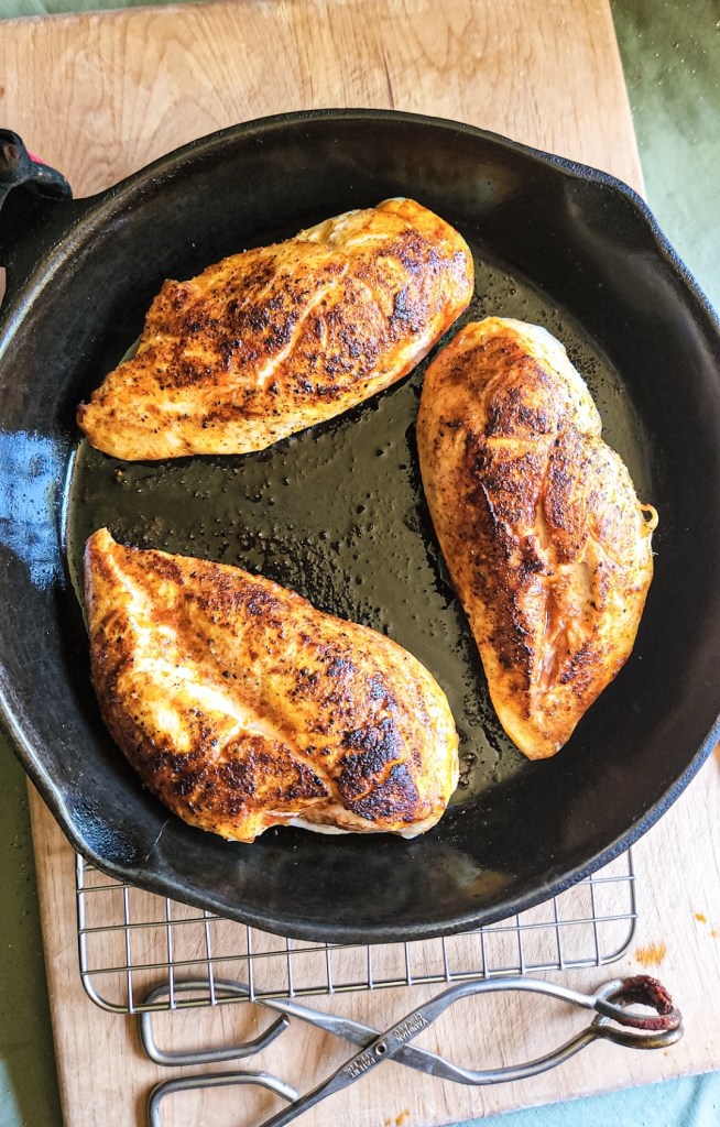 three chicken breasts seared in a cast iron skillet