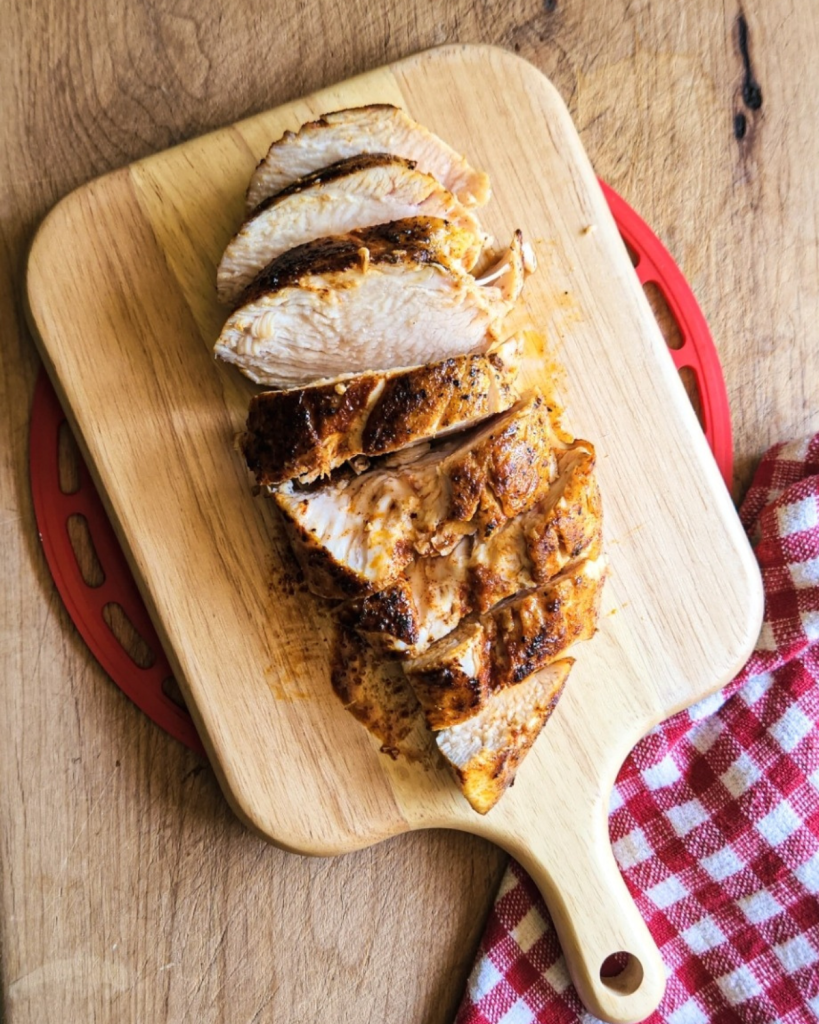 the best cast iron skillet chicken breast on a wooden paddle cutting board cut into pieces