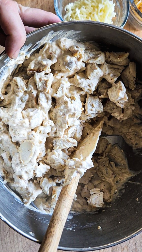 folding in the browned chicken breast into the creamy cheese mixture for the gluten free green chile chicken skillet recipe