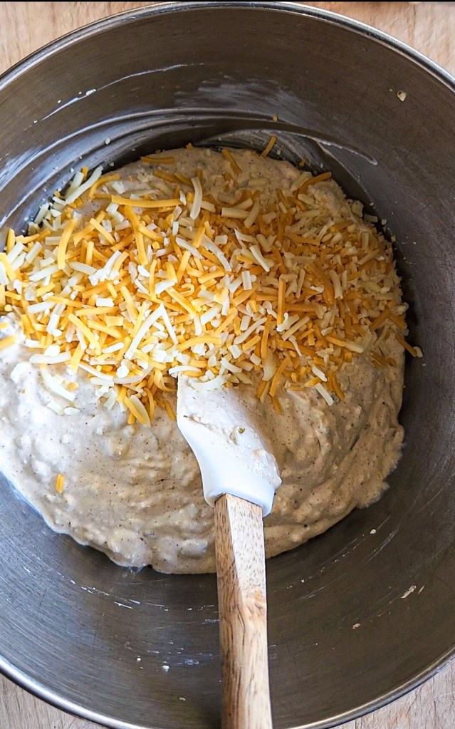 adding in half of the shredded cheese for the gluten free green chile chicken skillet recipe