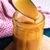 keto caramel sauce dripping from a spoon into a jar