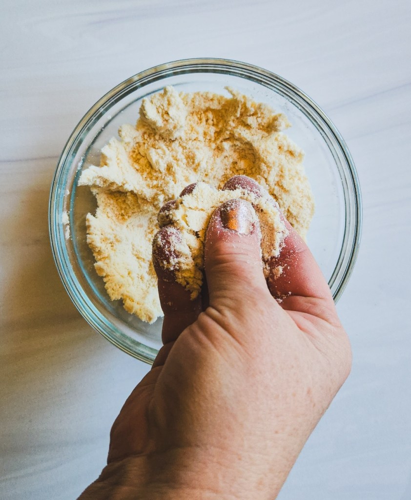 Breaking up coconut flour with fingers.