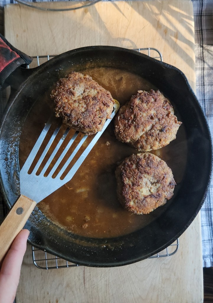 Gluten free Salisbury steak patties going into the brown gravy