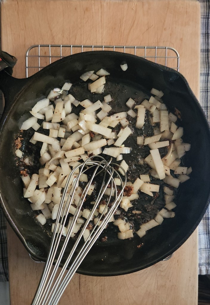 Onions sauteed in a cast iron pan for gluten-free Salisbury steak