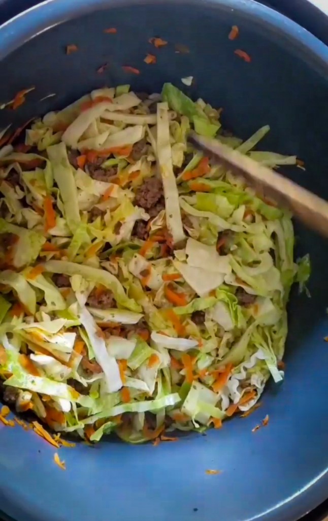 Cabbage and carrots being stirred into the instant pot low carb Egg Roll in a bowl