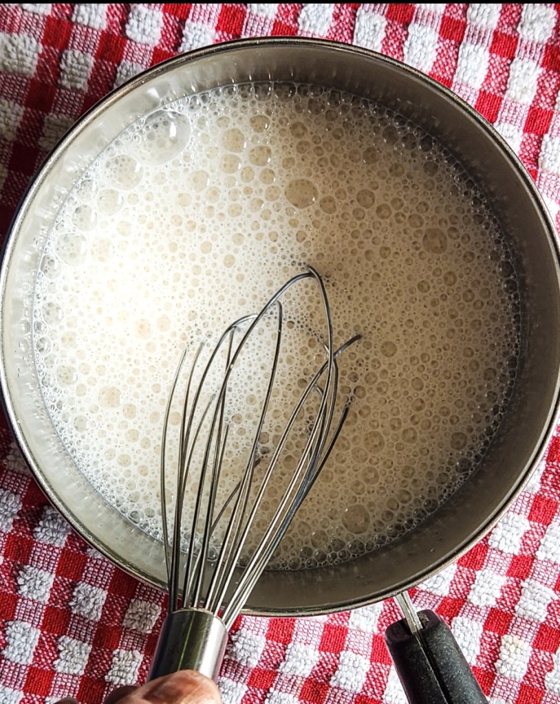 whisking warmed milk in a pan with a whisk.
