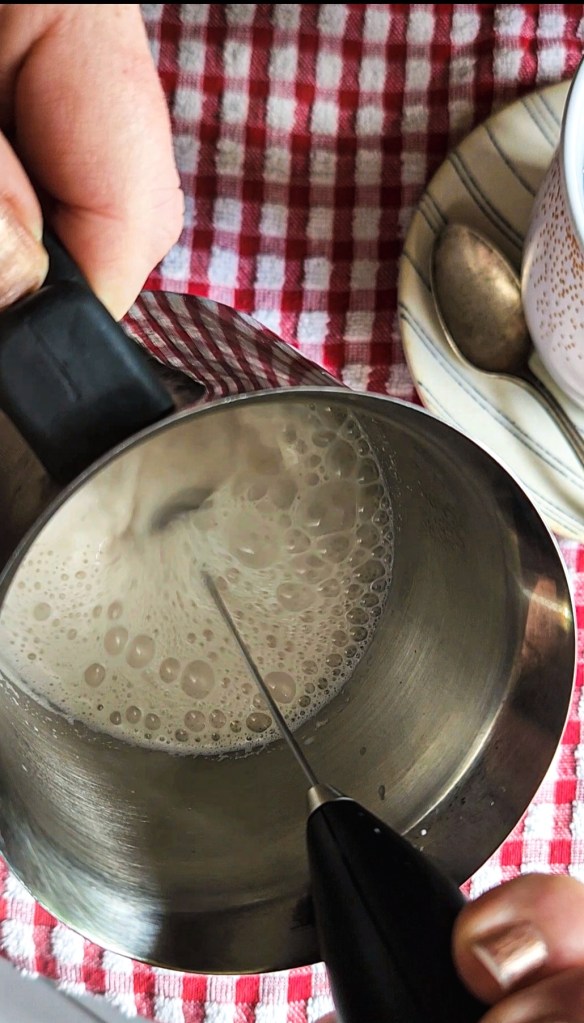 using frothing wand to froth milk.
