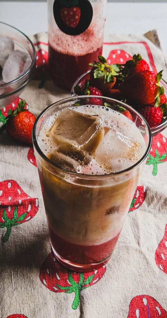 ice in a glass with strawberry syrup, unsweetened milk and topped off with coffee.