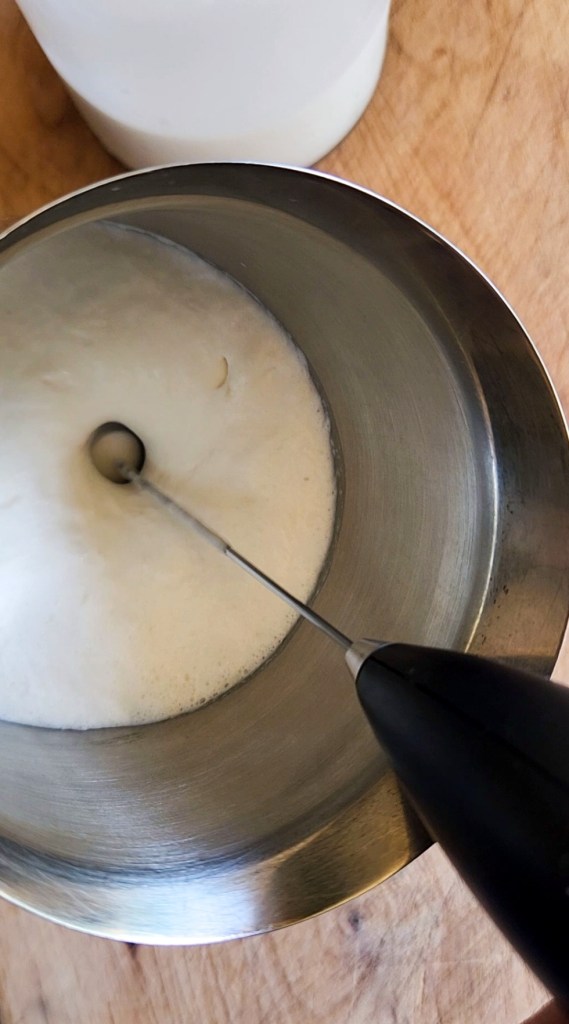 Frothing homemade creamer and a handheld frother pitcher