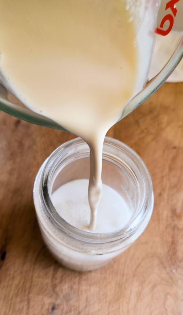 pouring leftover cold foam in a jar.