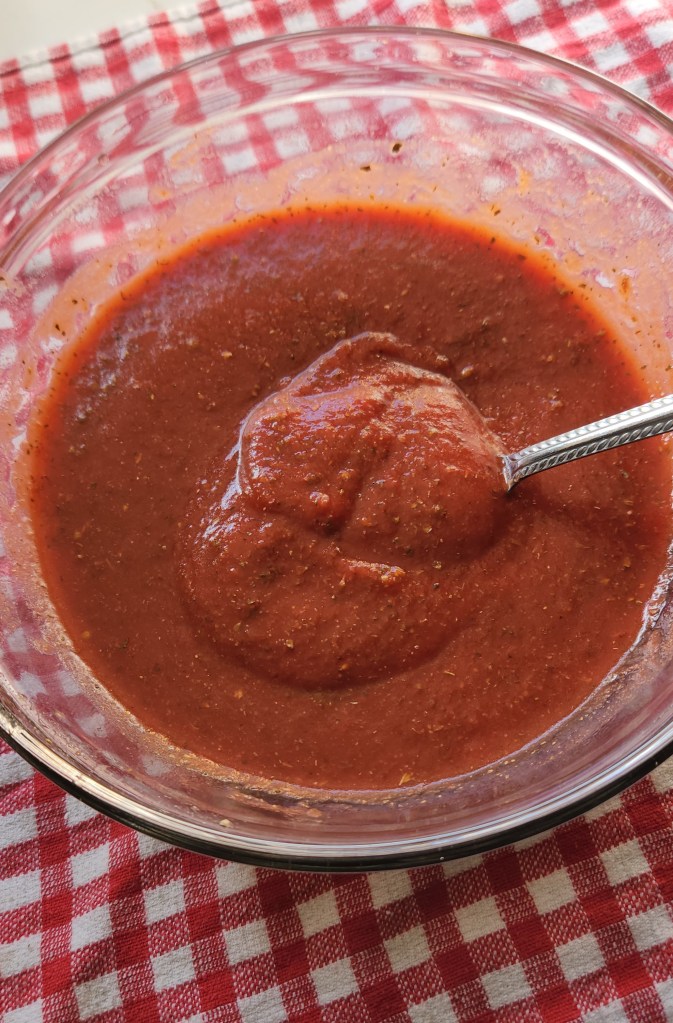 Low carb pizza sauce from one can of tomato paste in a bowl with a spoon