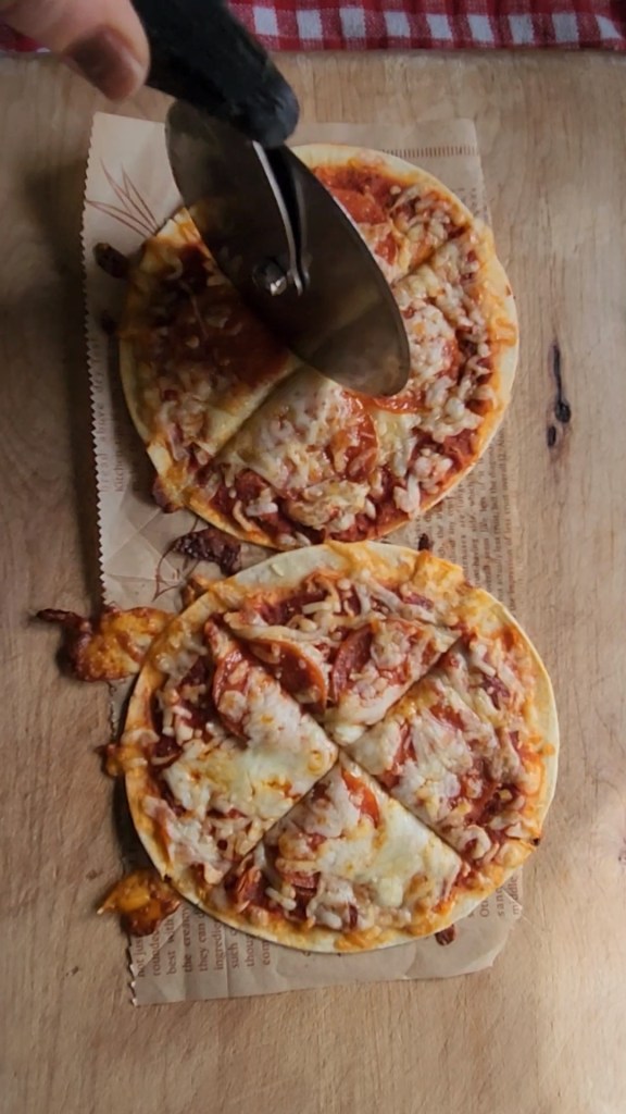 cutting the easy gluten free low carb tortilla pizza with a pizza cutter.