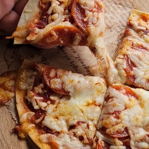 a piece of easy gluten free low carb tortilla pizza being pulled up.