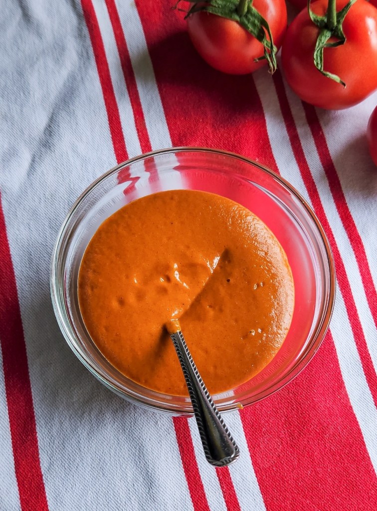 Easy low carb gluten-free recipe for enchilada sauce completed and in a bowl with a spoon.