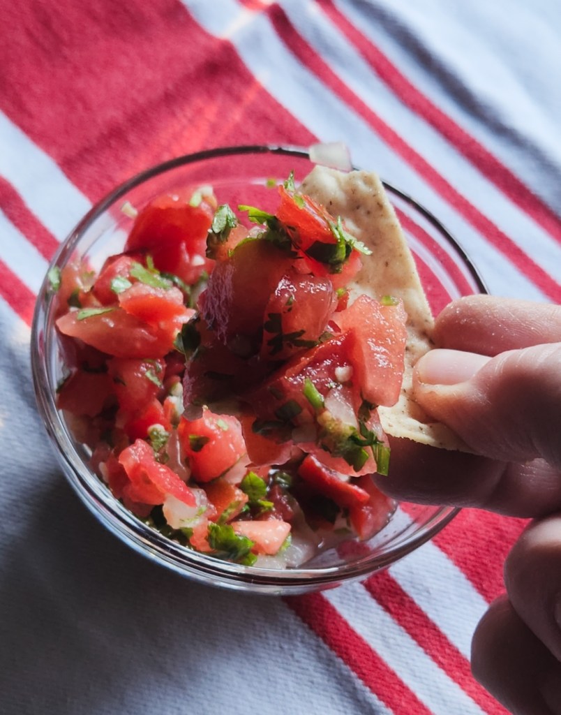 pico de gallo scooped up with a tortilla chip from a small bowl to serve.