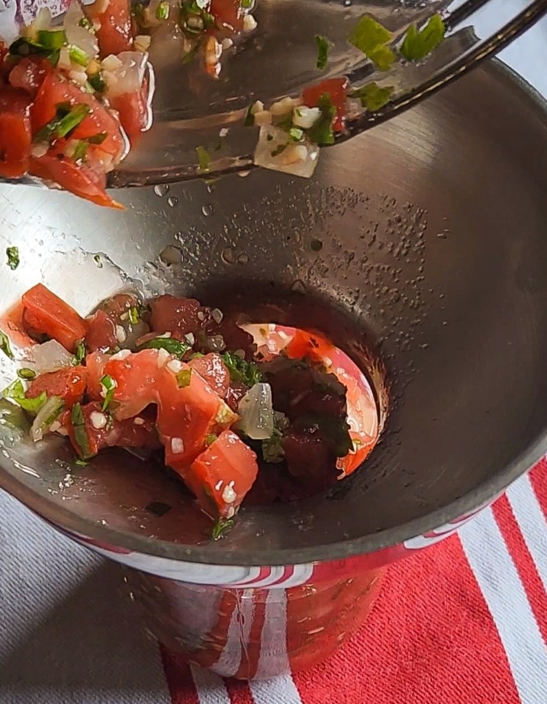 pouring the leftover pico de gallo into a quart jar.