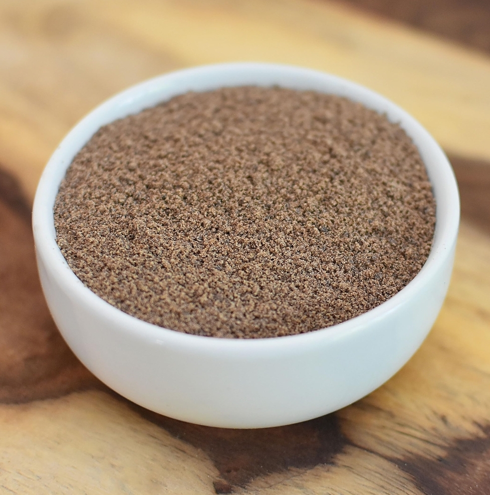 dark brown flaxseed meal in a white bowl.