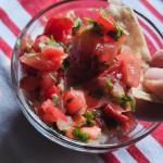 fresh pico de gallo being dipped into with a tortilla chip.