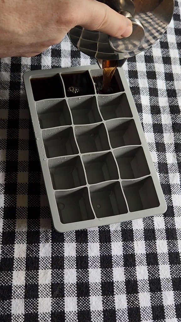 Pouring leftover coffee into an ice Cube tray.