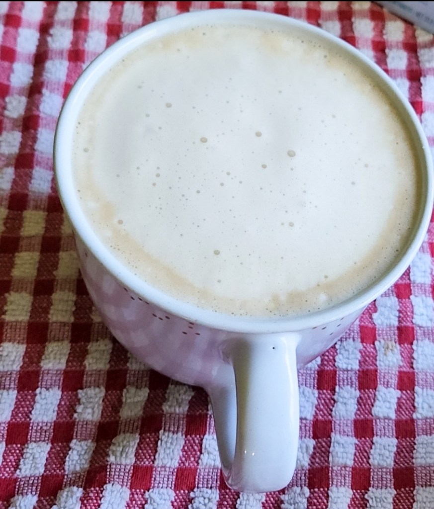 Coffee with creamer in a large white mug.