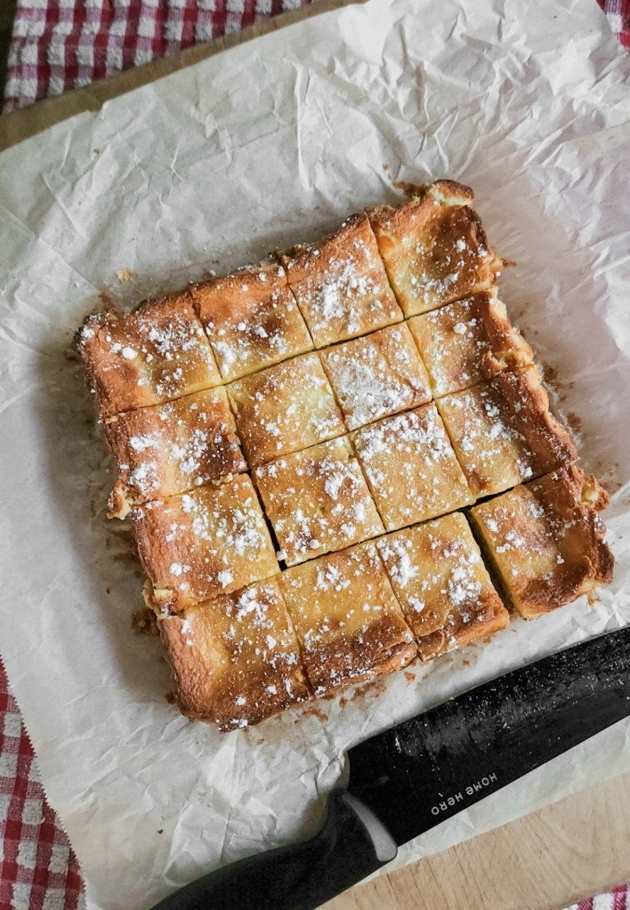 Keto gooey butter cake on parchment cut into pieces.
