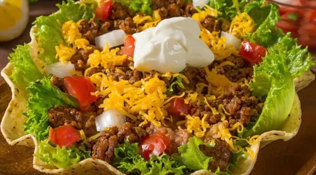 Taco salad topped with sour cream and all the fixings.