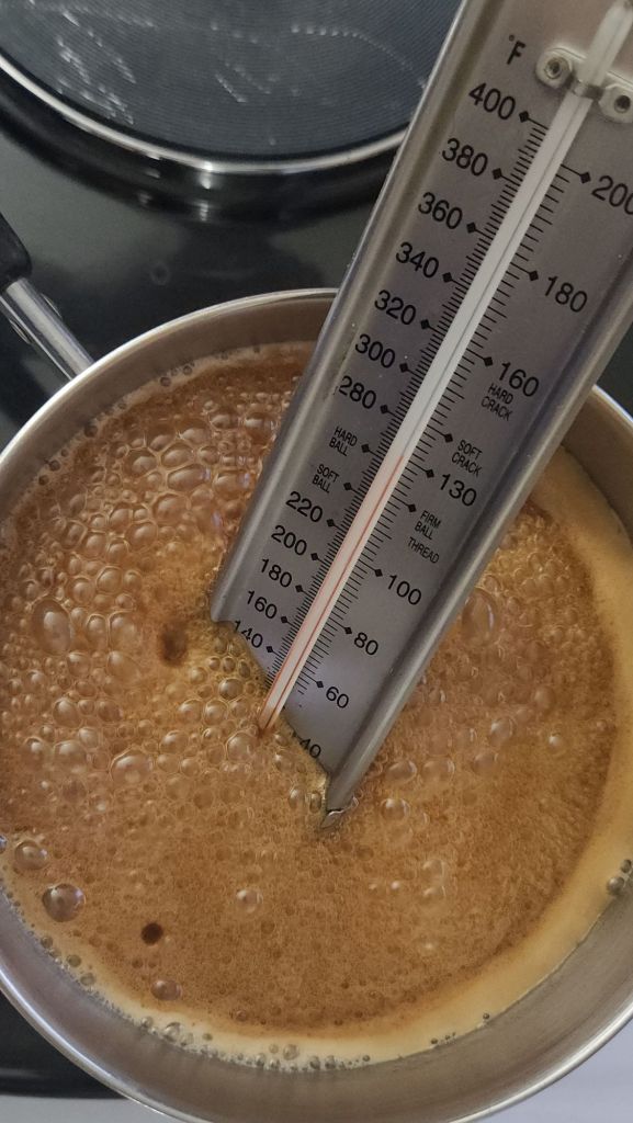 Caramel coating for low-carb caramel popcorn temperature being measured.