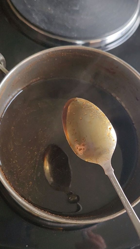 Checking to see if the syrup is done by dipping in a spoon and seeing if it's coated.
