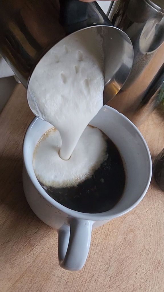 Topping low carb gingerbread latte with foamed dairy-free creamer.