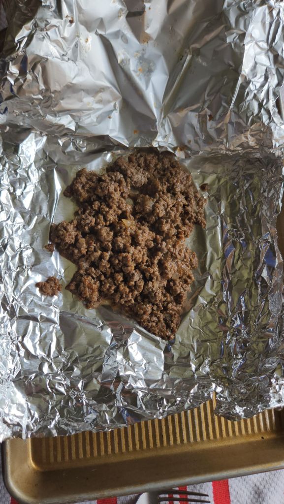 taco meat reheated in a foil packet on a baking sheet from the oven.