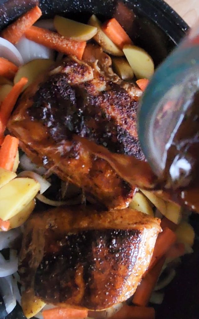 Pouring deglazed liquid over pork loin in roaster before roasting in oven.
