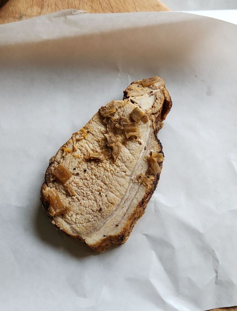 A slice of cooked pork loin on a pizza freezer paper.