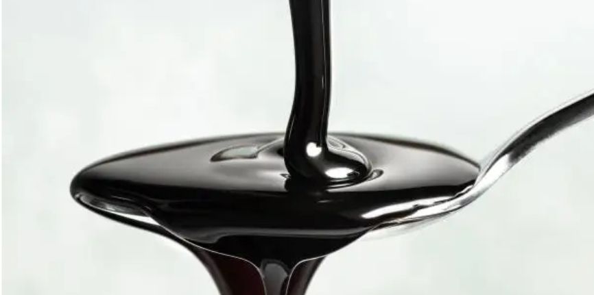 Molasses being poured on a spoon.