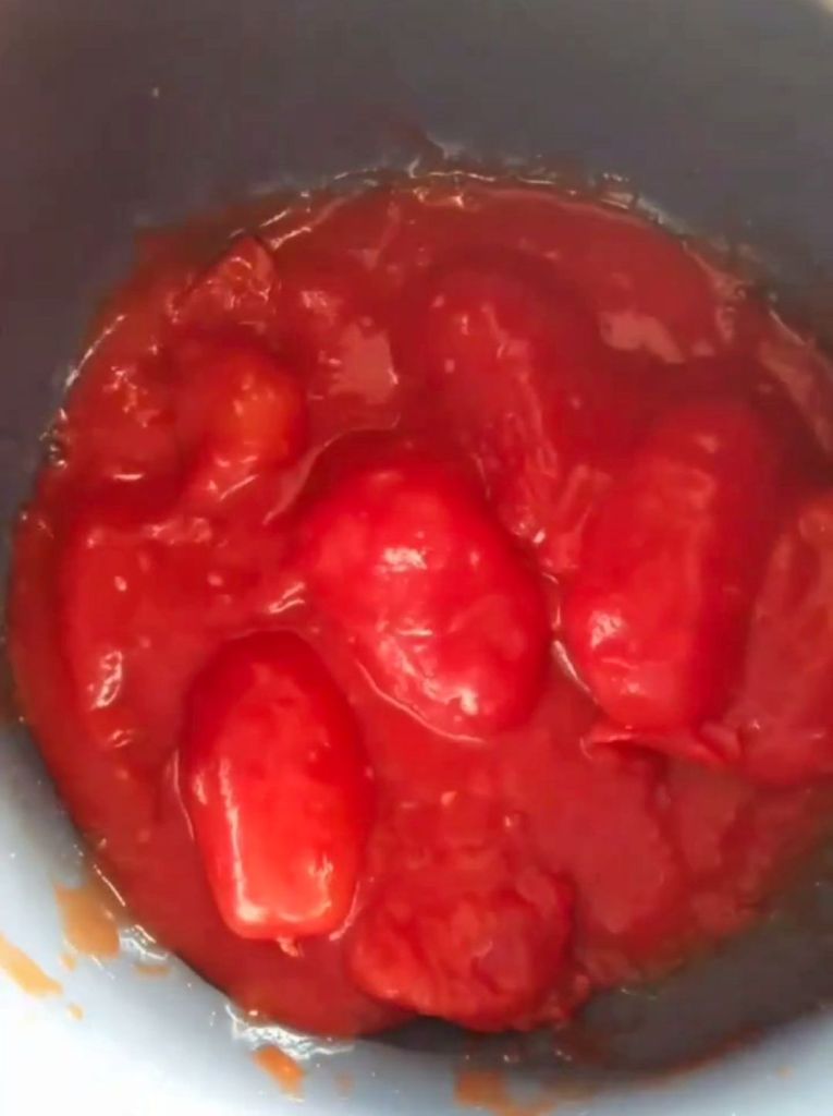adding whole tomatoes to the pot.
