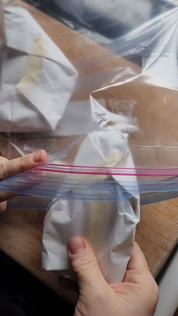 Putting wrapped single pieces of cooked pork loin in a freezer bag.