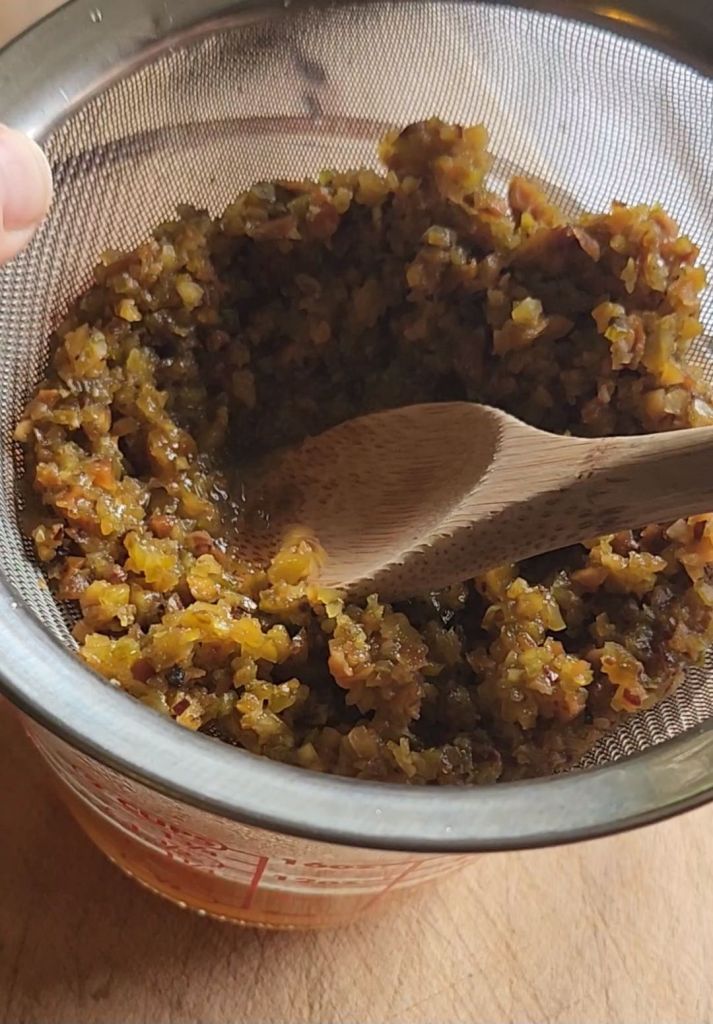 Pressing the low carb copycat Starbucks pistachio latte syrup from the pistachios in a sieve.