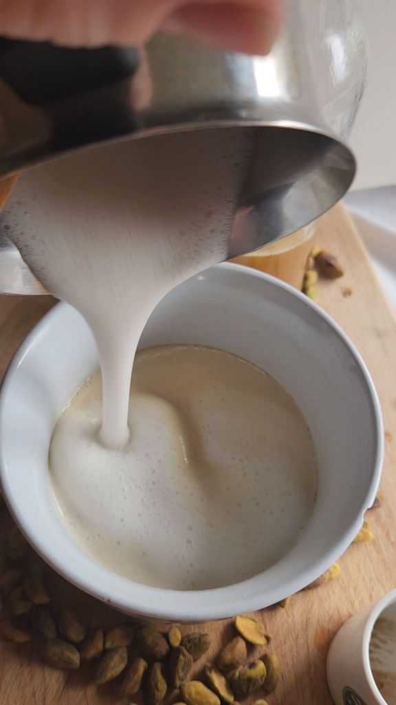 Pouring from milk into a low-carb copycat Starbucks pistachio latte.