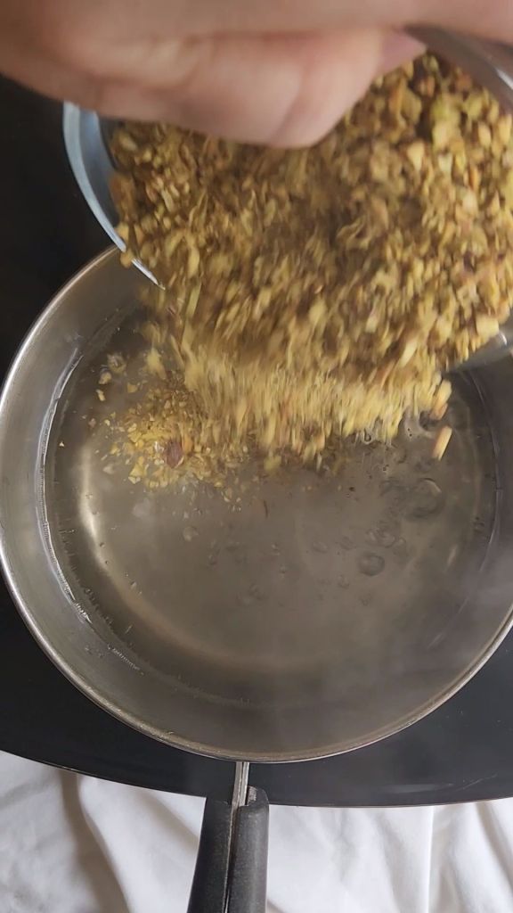 Pouring pistachios into a small saucepan to create low carb copycat Starbucks pistachio latte syrup.