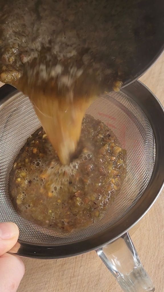 Straining chopped pistachios from the low carb copycat Starbucks pistachio latte syrup created.