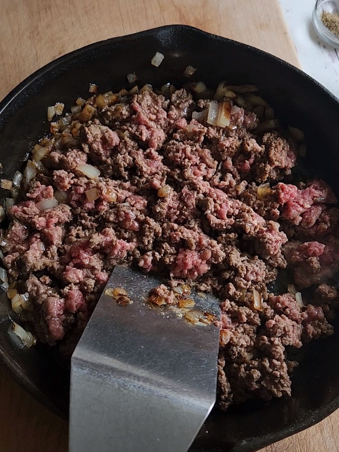 Breaking up and Browning ground beef in a cast iron skillet.