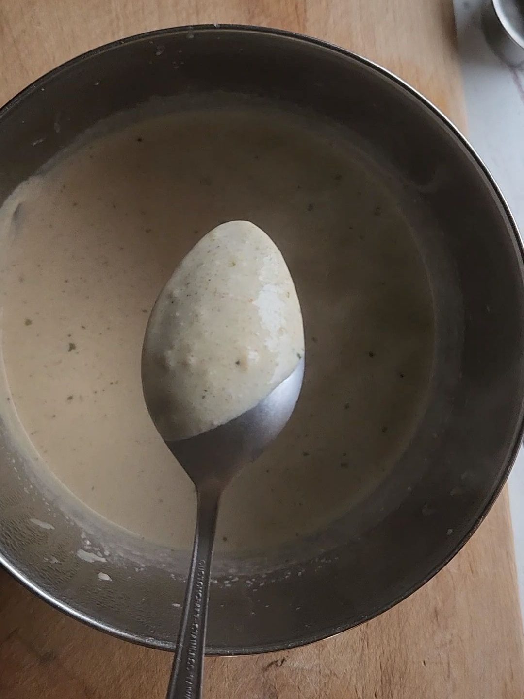 Checking to see if the homemade cream soup is ready by dipping in a spoon to see if it's coated.