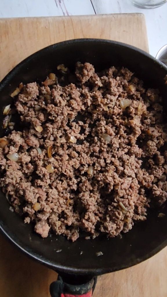 Ground beef browned and crumbled in a skillet.